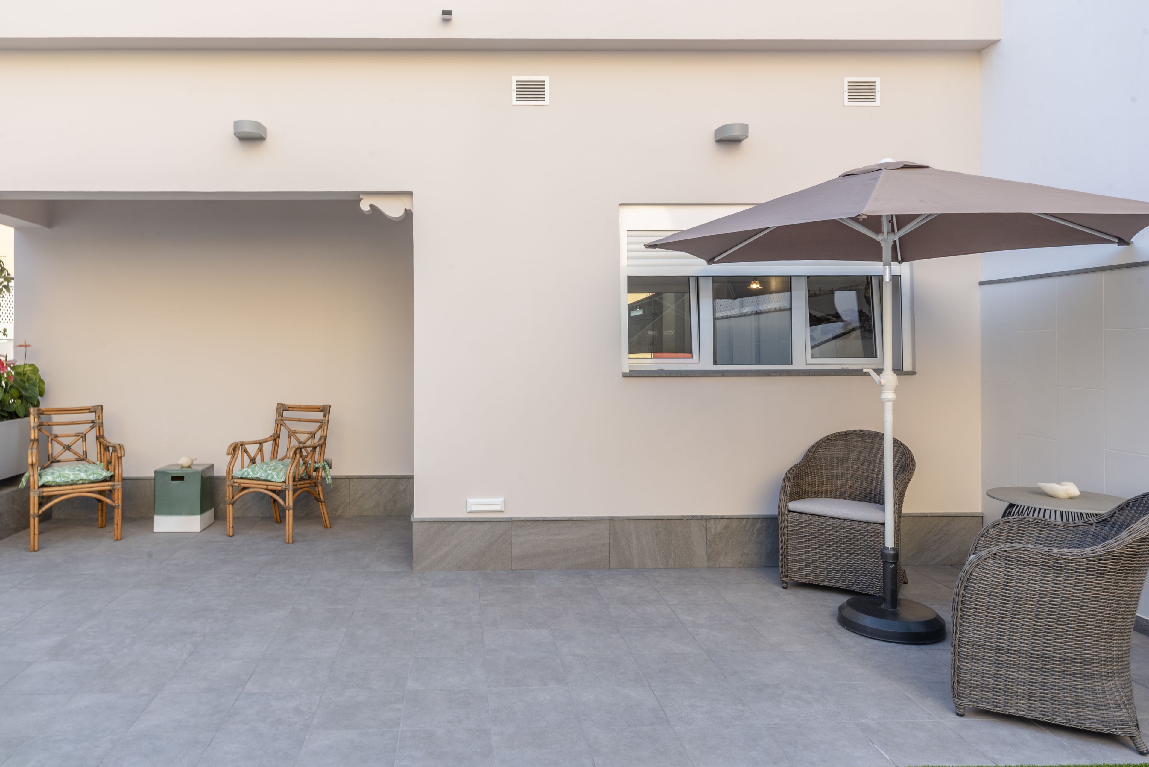 An outdoor patio area with wicker furniture, a table, and a large umbrella.