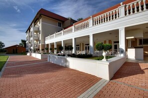 Un hotel de varios pisos con un espacio al aire libre cubierto, un camino de ladrillo y un jardín bien cuidado.