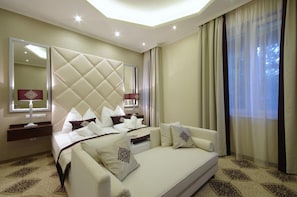 Una habitación de hotel con una cama grande, un sofá, un espejo y una ventana con cortinas.