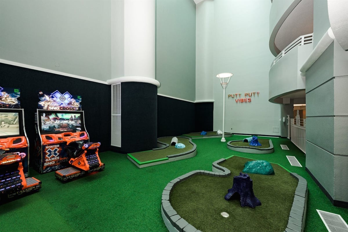 A miniature golf course with two arcade games and a 'Putt Putt Vibes' sign.