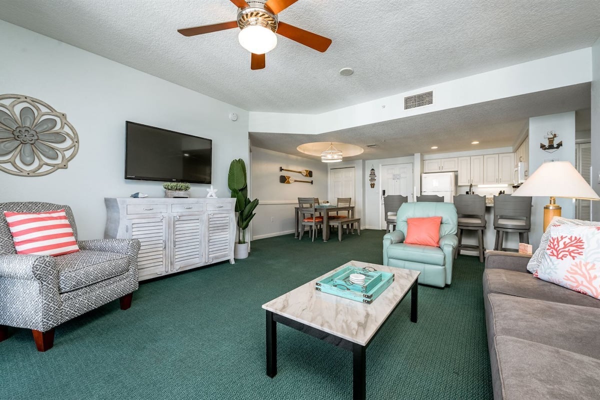 A living room with a TV, a dining area, and a kitchen.