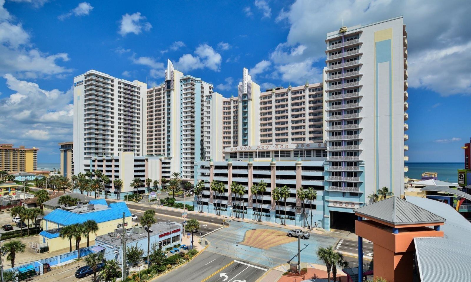 Un hôtel de grande hauteur, avec de nombreux étages, un parking et une vue sur la plage.