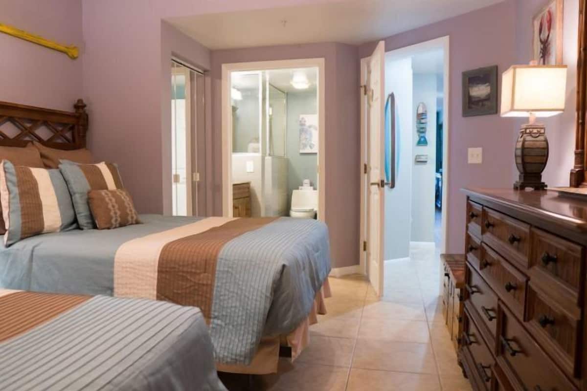 A bedroom with two beds, a wooden dresser, and a mirror.