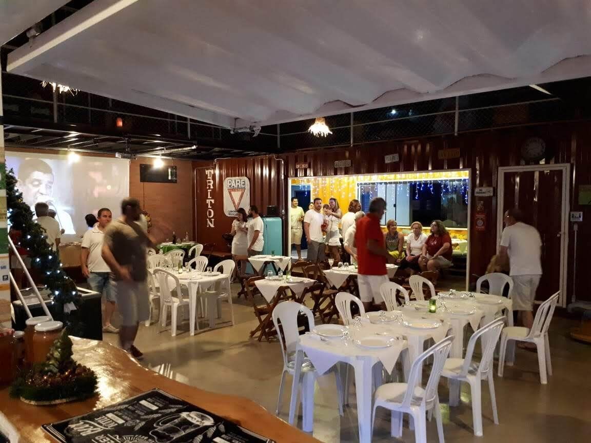 A restaurant with white tables and chairs, a Christmas tree, and a bar area.
