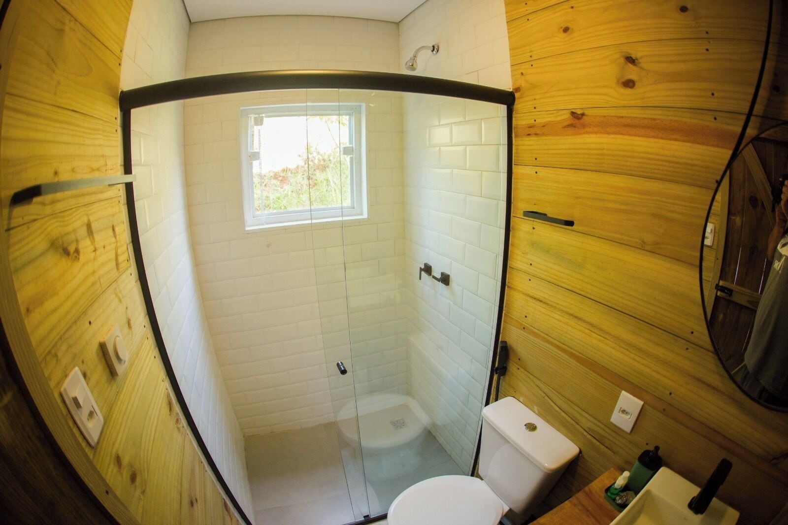 A compact bathroom with a glass shower enclosure, a toilet, and a sink.