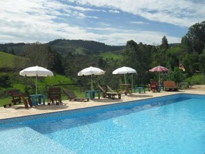 Una piscina al aire libre, sillones reclinables de piscina