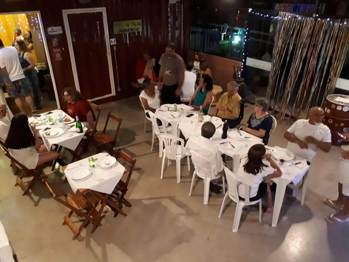 An outdoor dining area with tables and chairs, some occupied by people.