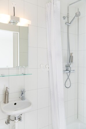 A modern bathroom with a white sink, mirror, and shower.