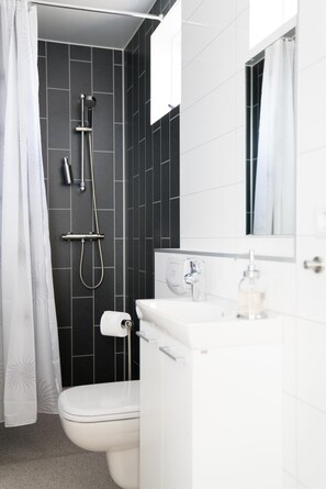 A modern bathroom with a shower, toilet, and sink.