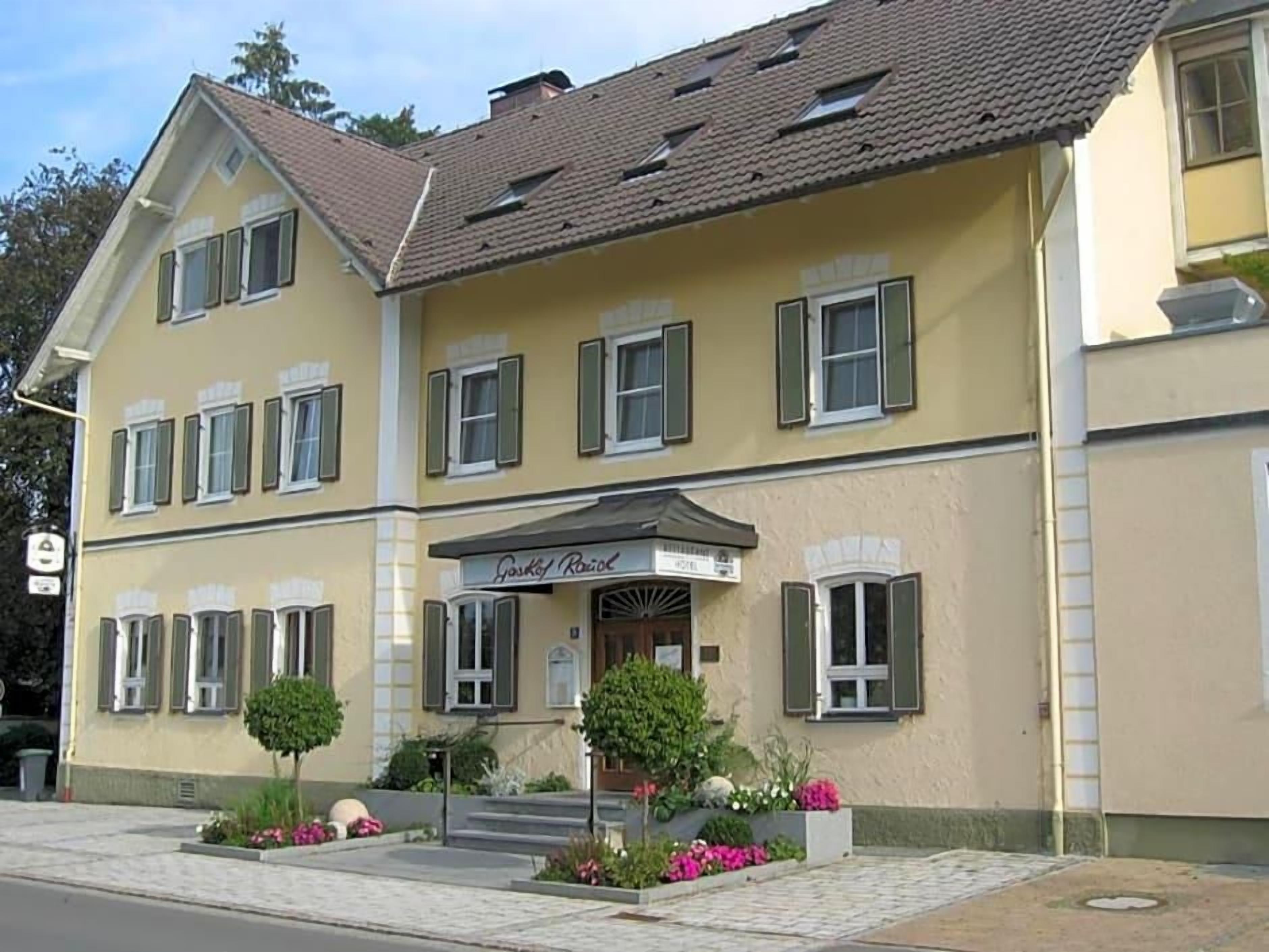A two-story building with a yellow facade, multiple windows with shutters, and a sign indicating a restaurant.