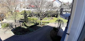 A paved pathway leading to a building with a balcony.