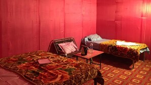Una habitación con dos camas, una mesita y una silla.