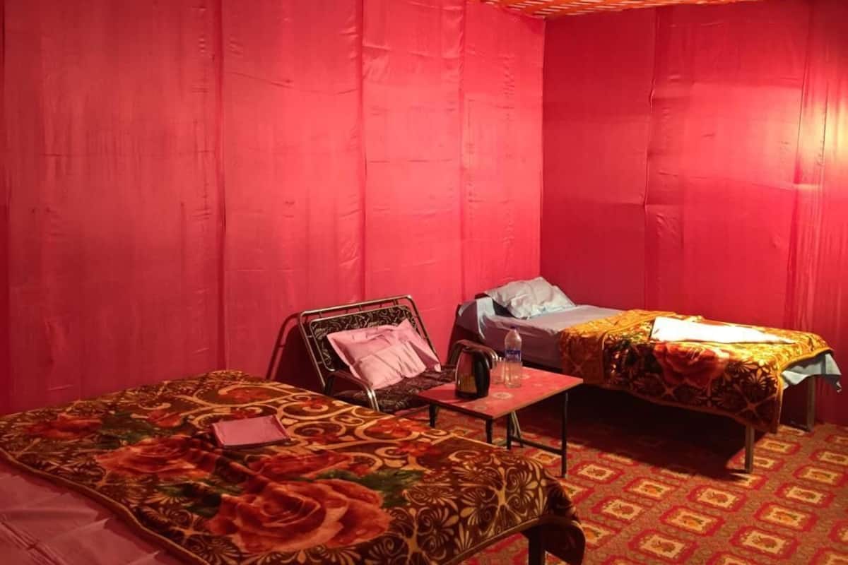 A room with two beds, a small table, and a chair.