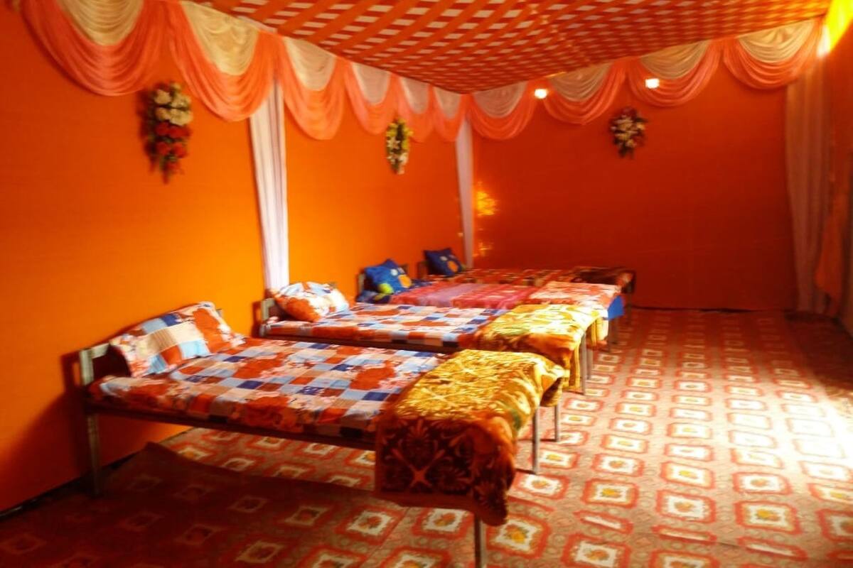 A room with three beds, orange walls, patterned floor, and a checkered ceiling.