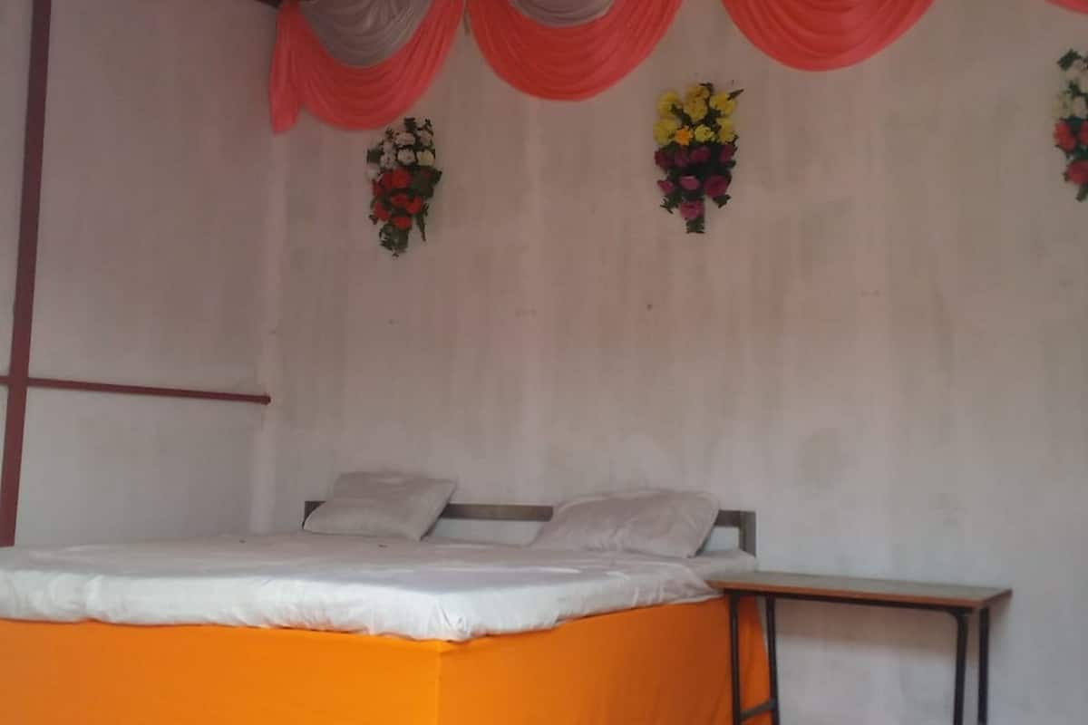 A bedroom with a bed, a nightstand, and two wall-mounted flower arrangements.