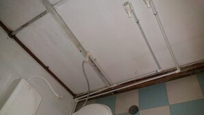 Un baño pequeño con azulejos, un inodoro, fontanería a la vista y un piso con estampado de cuadros.