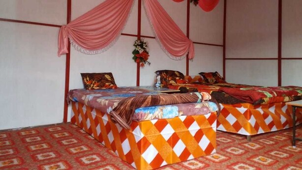 Una habitación con dos camas, cada una con ropa de cama estampada y una mesa entre ellas.