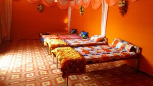 Una habitación con cuatro camas dispuestas en fila, paredes naranja y suelo estampado.