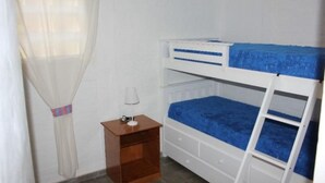 A bunk bed room with a white headboard, a small wooden nightstand, and a white lamp.