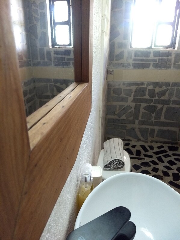 A bathroom with a stone wall, a wooden window frame, a white sink, and a towel. - Hotel Beyonda (Santa Marta)