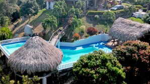 A large house with a swimming pool, surrounded by lush greenery and palm trees. - Hotel Beyonda (Santa Marta)