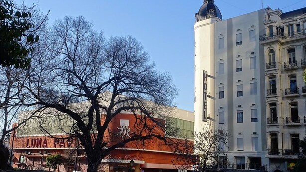 A hotel with a prominent tower, a red building with 'LUNA PARK' signage, and a street with pedestrians.
