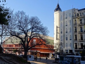 Un hôtel doté d’une tour imposante, un bâtiment rouge avec une enseigne indiquant « LUNA PARK », et une rue bordée de piétons.