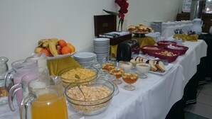 A buffet table with various food items, including fruits, cereals, and beverages.