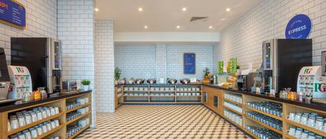 A café with a checkered floor, shelves with cups and glasses, and a sign for bringing home the bacon.