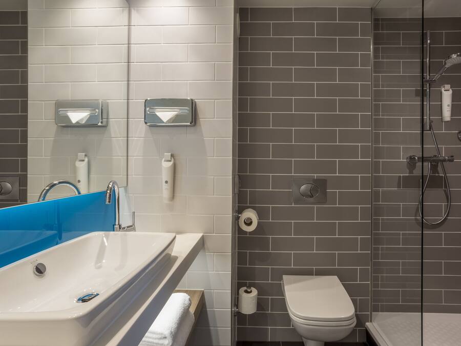 A modern bathroom with a white sink, blue shower enclosure, and a glass shower stall.