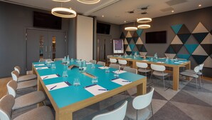 A conference room with a long table, chairs, and a projector screen. - Holiday Inn Express Bridgwater M5, Jct. 24 by IHG (Bridgwater)