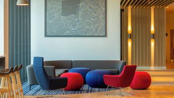 A modern lobby with a large map on the wall, a grey sofa, and red and blue chairs.