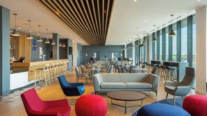 A modern interior with a bar area, seating arrangements, and large windows. - Holiday Inn Express Bridgwater M5, Jct. 24 by IHG (Bridgwater)