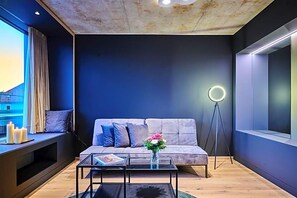 Moderni olohuone, jossa on sohva, sohvapöytä, lattiavalaisin ja ikkuna, jossa on verhot.