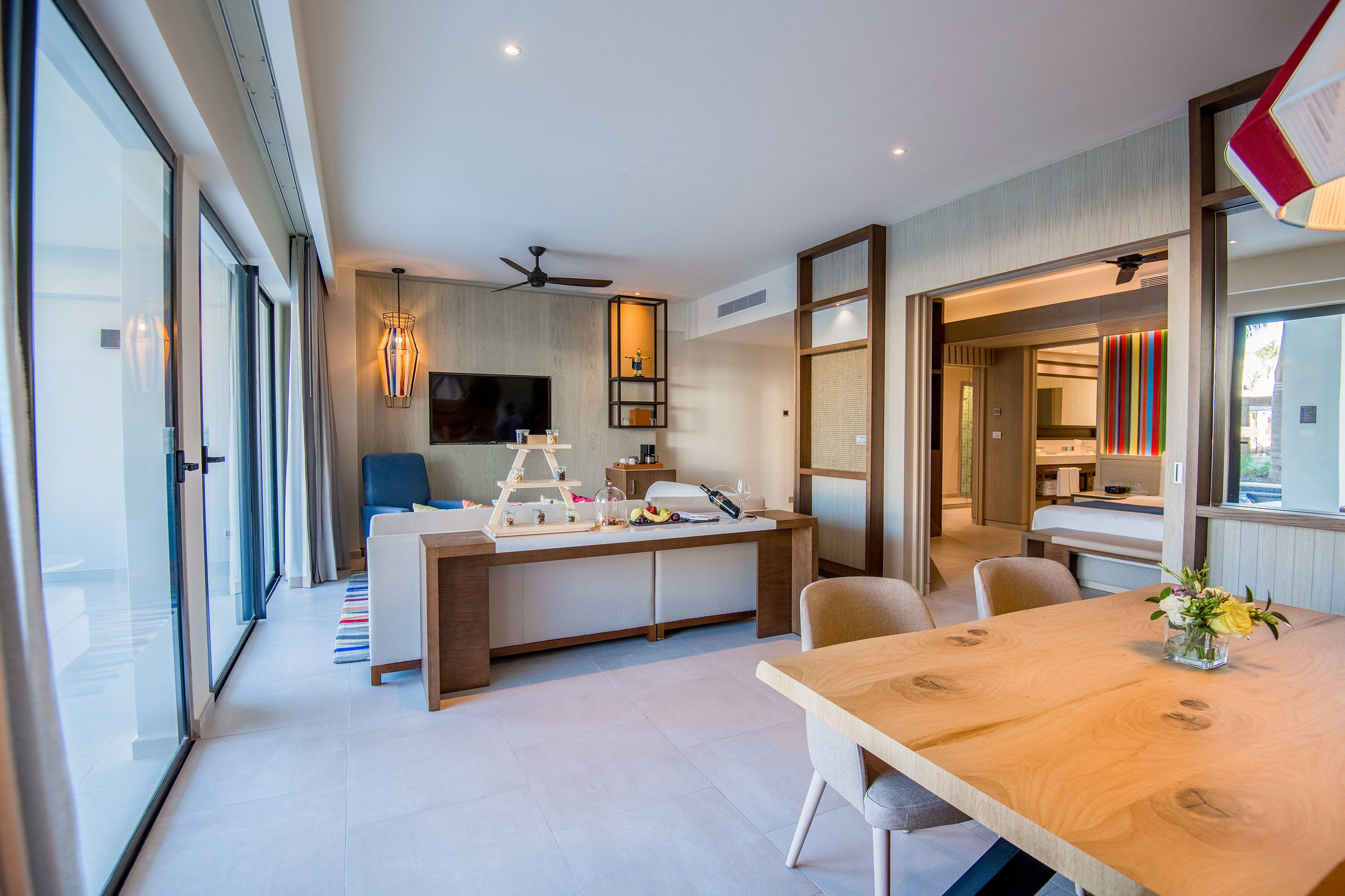 A modern kitchen with a central island, a dining area with a wooden table, and a large window providing natural light.