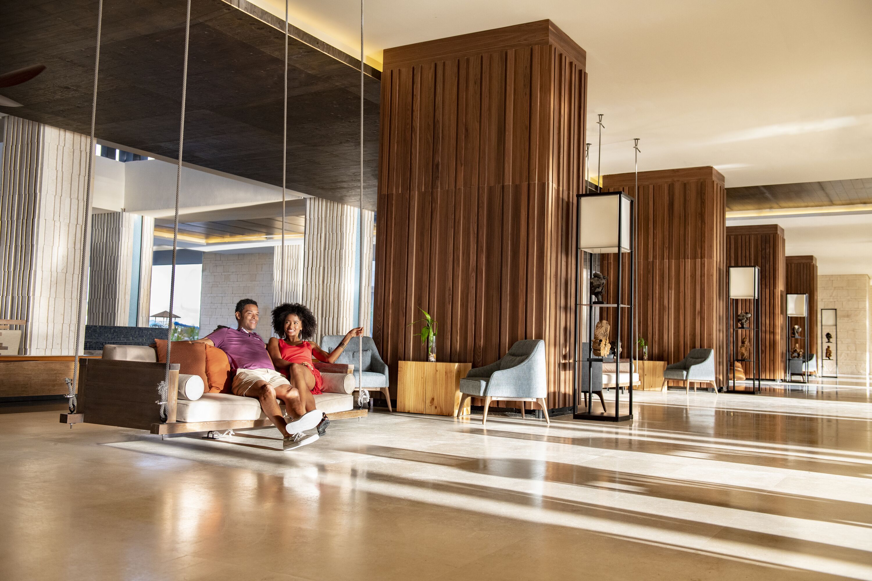 Un vestíbulo moderno con una zona de estar suspendida, paneles de madera y mobiliario contemporáneo.