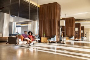 A modern lobby with a suspended seating area, wooden paneling, and contemporary furniture.