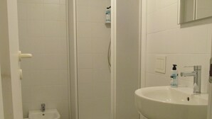 Een badkamer met een douche, toilet, wastafel en bidet.