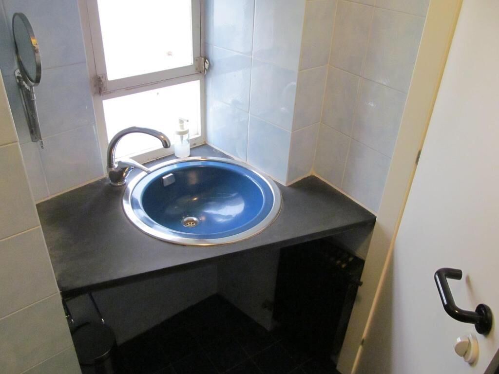 A bathroom with a blue sink, a window, and a door with a handle.
