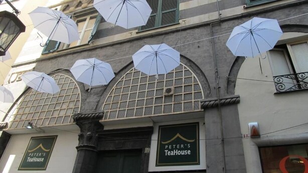 Een gevel met meerdere witte parasols die eraan hangen.