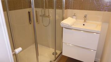 Un baño moderno con ducha de vidrio, lavamanos blanco y espejo sobre él.