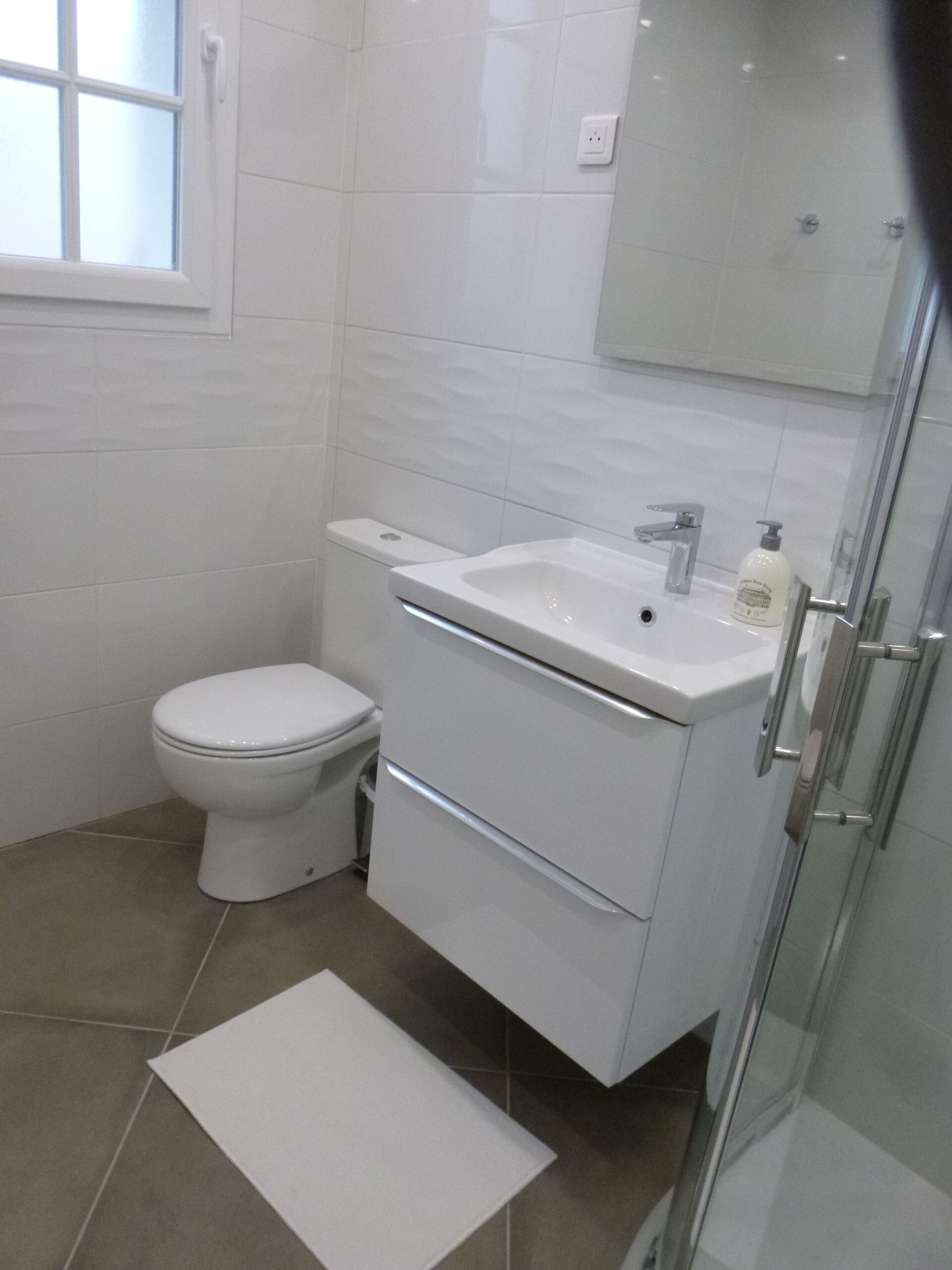 Un baño moderno con inodoro, lavamanos y ducha.