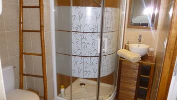 Ein Badezimmer mit Duschkabine, Toilette, Waschbecken und Spiegel.