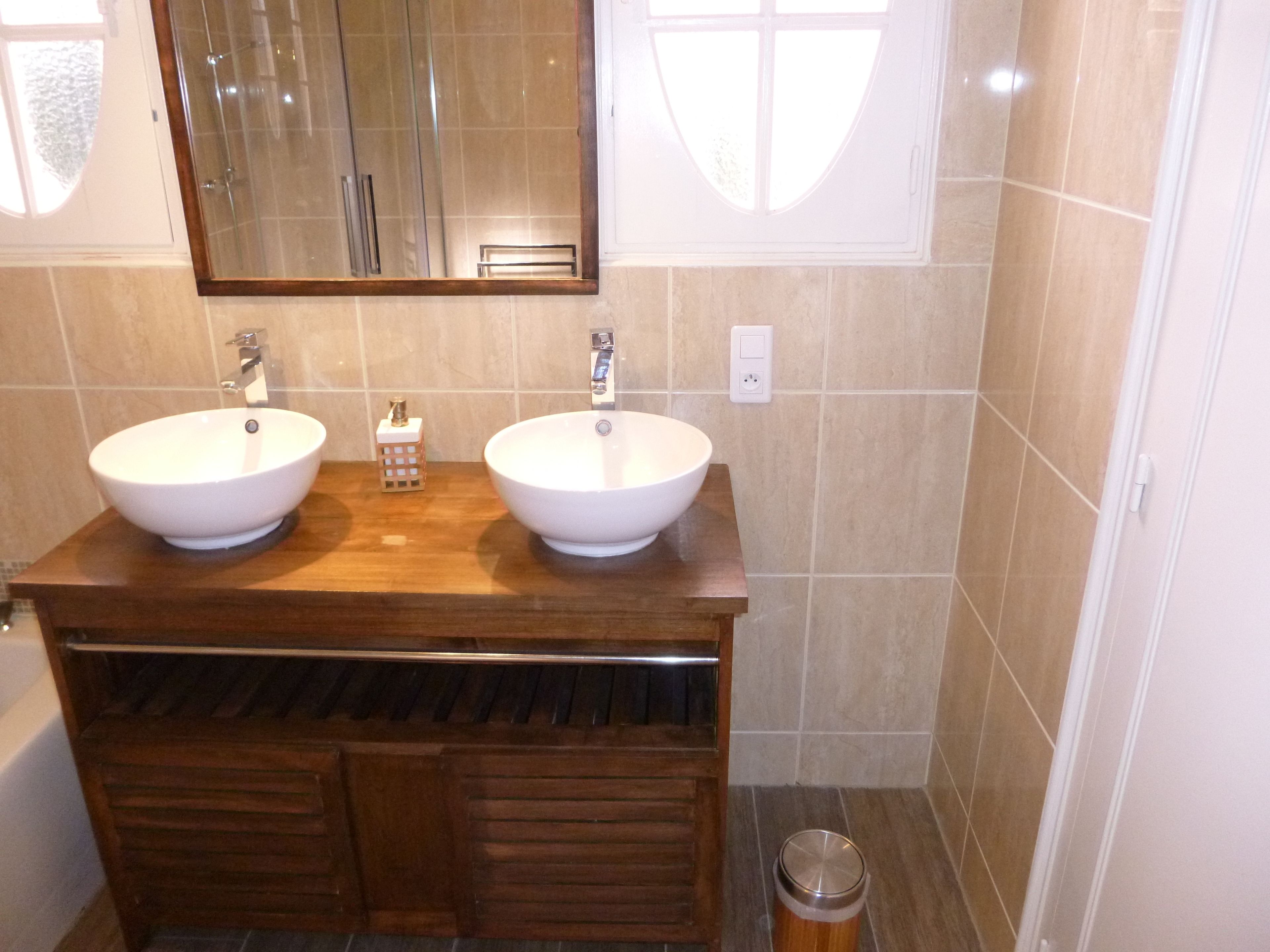 Un baño con dos lavamanos, un espejo y un mueble de tocador de madera.