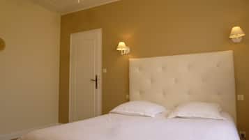 Un dormitorio con una cama grande, una puerta blanca y dos lámparas fijadas a la pared.
