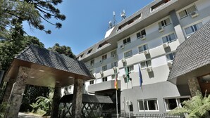 A multi-story hotel with a central entrance, surrounded by greenery and a paved area. - Tri Hotel Canela (Canela)