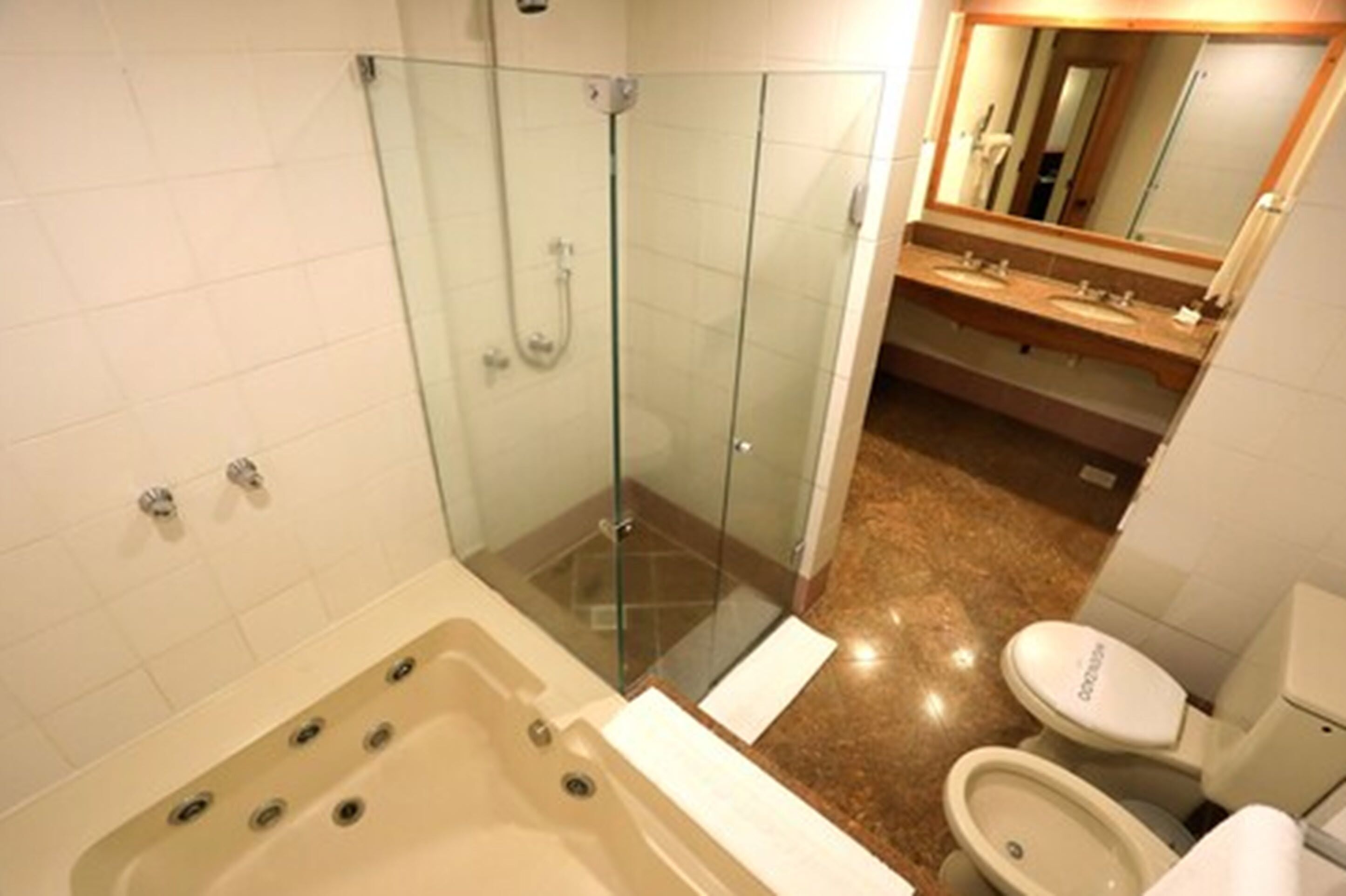 A bathroom with a glass-enclosed shower, a bathtub, a toilet, and a vanity with a mirror.