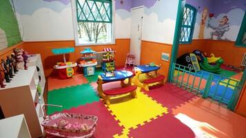 Children can play and explore in this vibrant playroom with play structures, tables, and a toy kitchen.