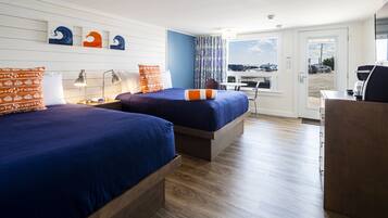 A hotel room with two beds, a desk, and a view of the parking lot.