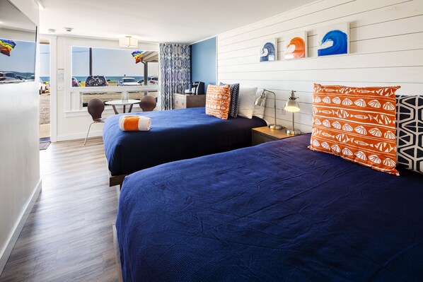 A hotel room with two beds, a desk, and a view of the beach. - Breakwater Hotel (Provincetown)